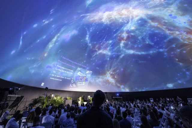 A dome audience seated beneath a projected galaxy