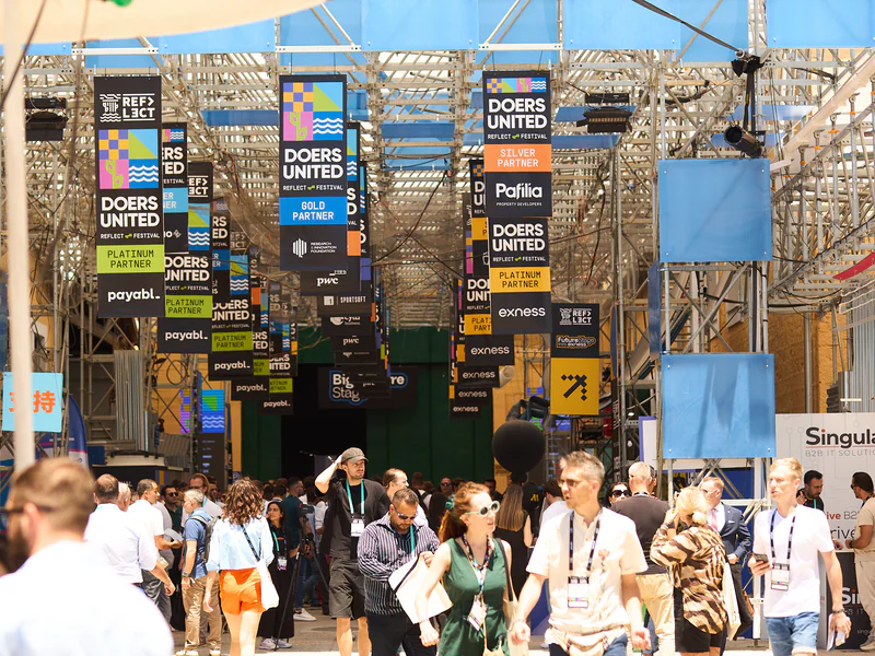 The expo boulevard under a canopy of partner banners, packed with attendees