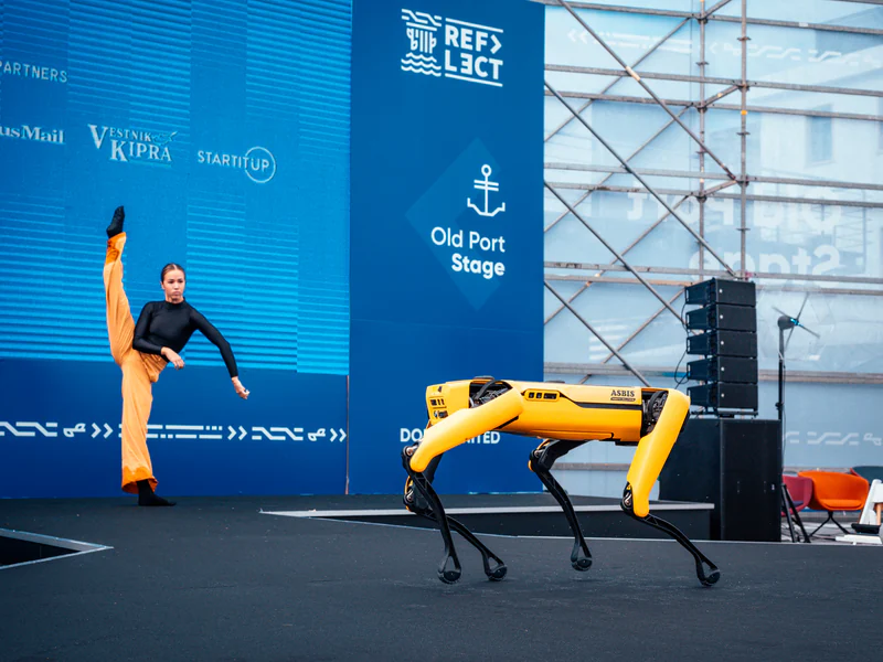 A robot dog on the Old Port Stage beside its handler
