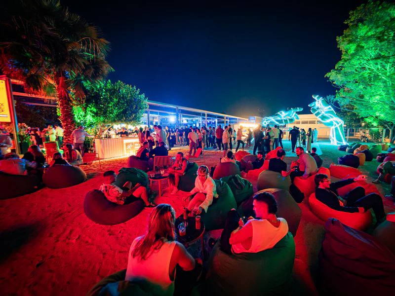 Guests on beanbags at an outdoor evening session under coloured lights